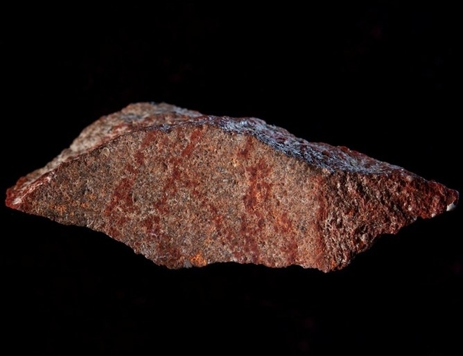 Малък камък с надраскани с охра кръстосани линии преди 73