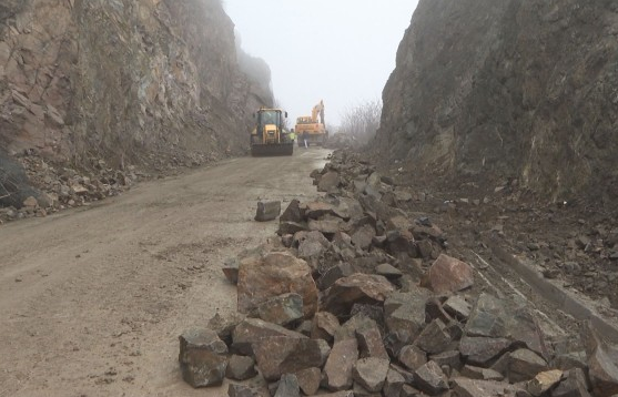 Работниците които почистват падналите камъни и земя на пътя през