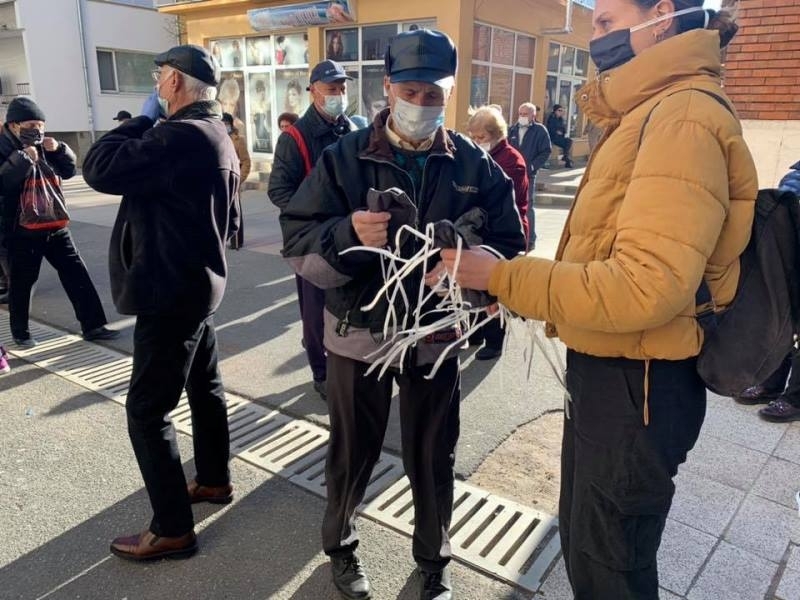 Доброволци раздават маски на възрастните хора които чакат за изплащенето