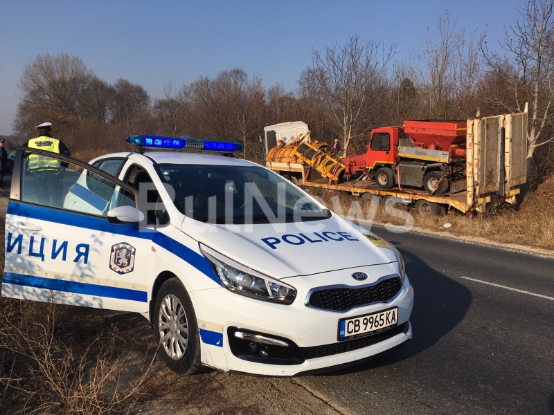 Шофьор на камион с платформа натоварена със снегопочистваща техника е